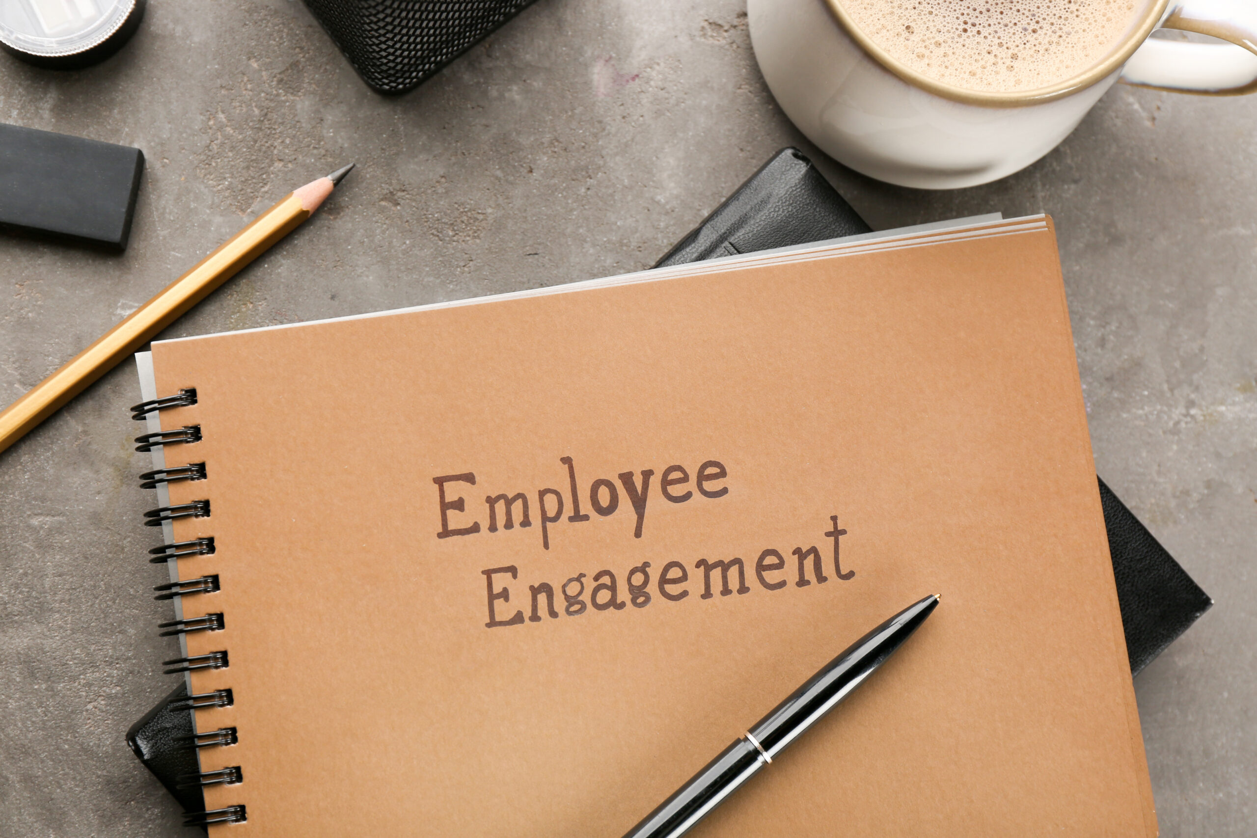 Notepad with text EMPLOYEE ENGAGEMENT on table